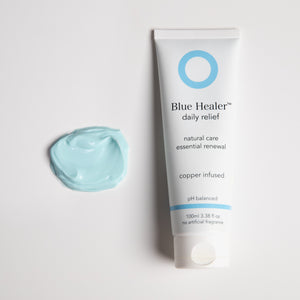 Blue Healer daily relief product tube next to a dollop of the naturally blue, shiny cream, 100 ml size. Relief, renewal and recovery cream. Vegan. Sensitive friendly.